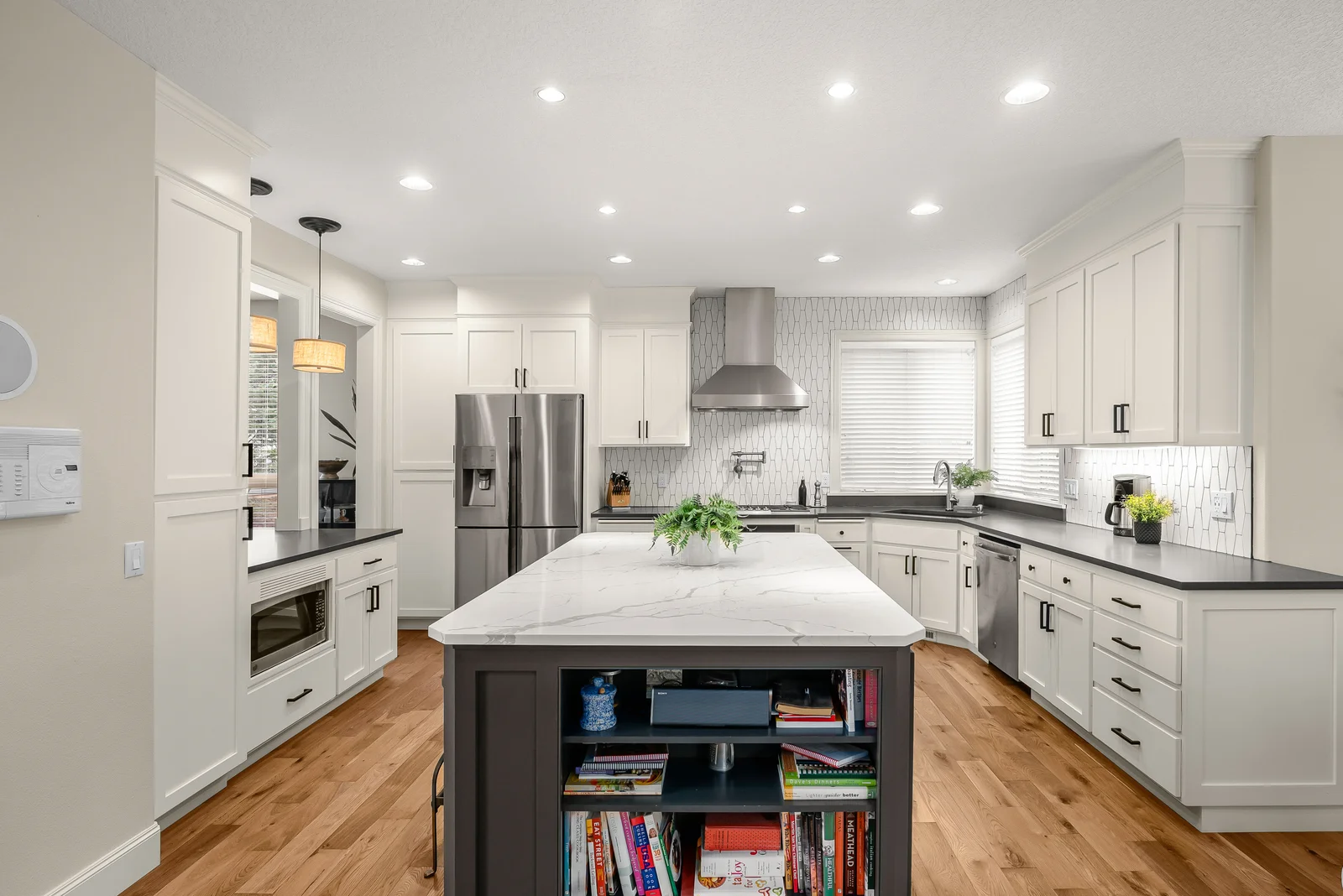 White kitchen cabinetry with a central island and dark countertops