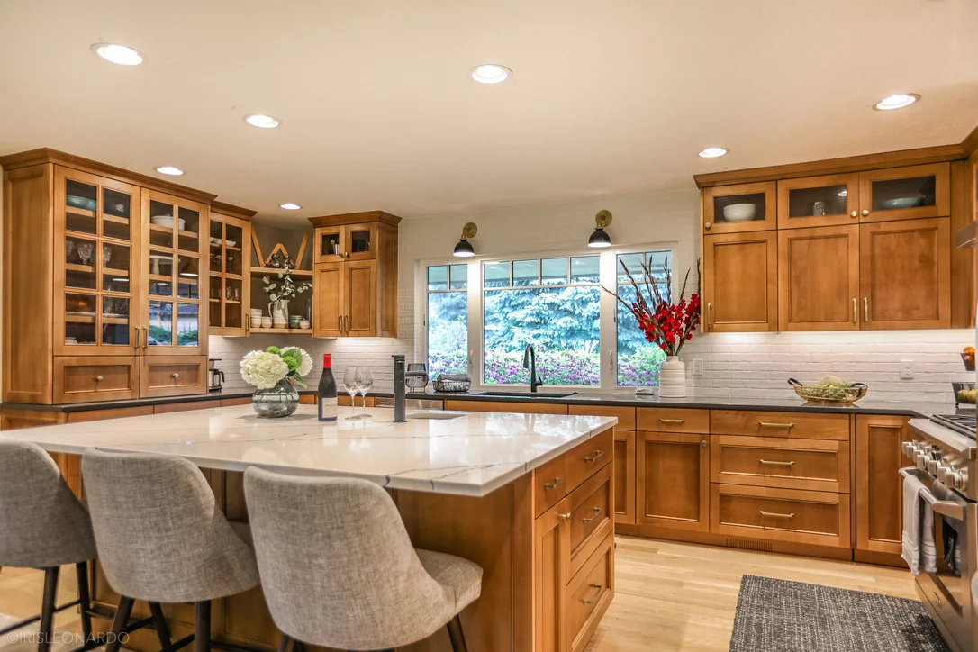 Warm wood kitchen cabinetry with glass-front upper cabinets and a central island